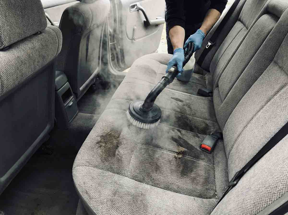 le siege arriere d une voiture avec piqure avec une main qui nettoie avec une mach 52852